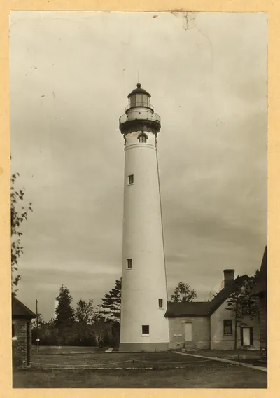 White lighthouse tower beside a brick keeper's house