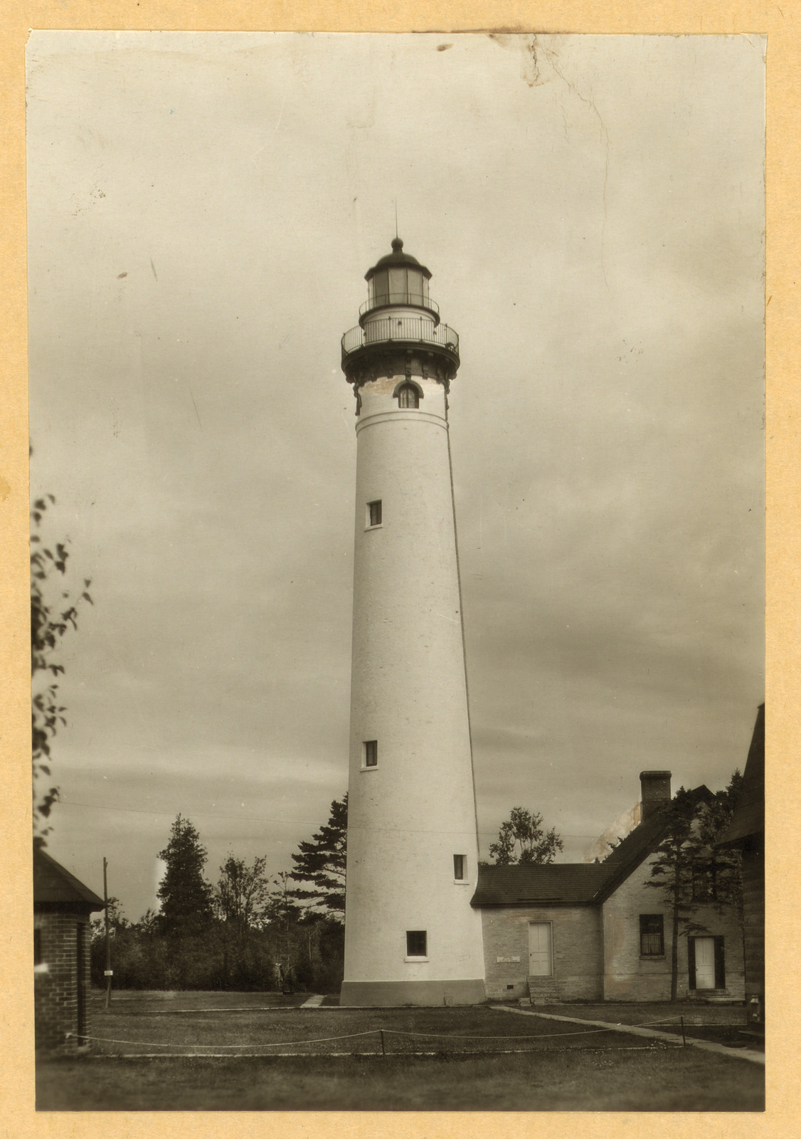 White lighthouse tower beside a brick keeper's house — historic image