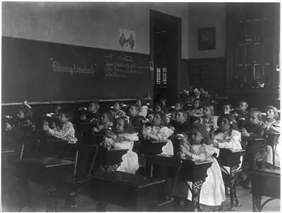 [Children in a classroom blowing pinwheels in a Washington, D.C., grade school]