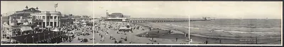 Panoramic photograph of a crowded beach with a long pier