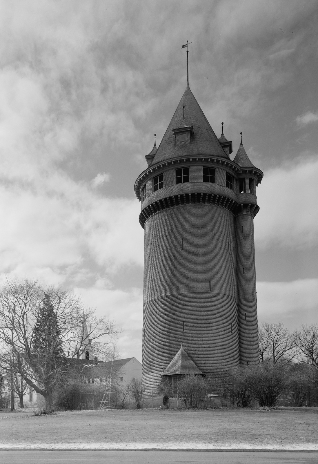 Shingled water tower with turrets and weathervane, black and white photograph — historic photograph