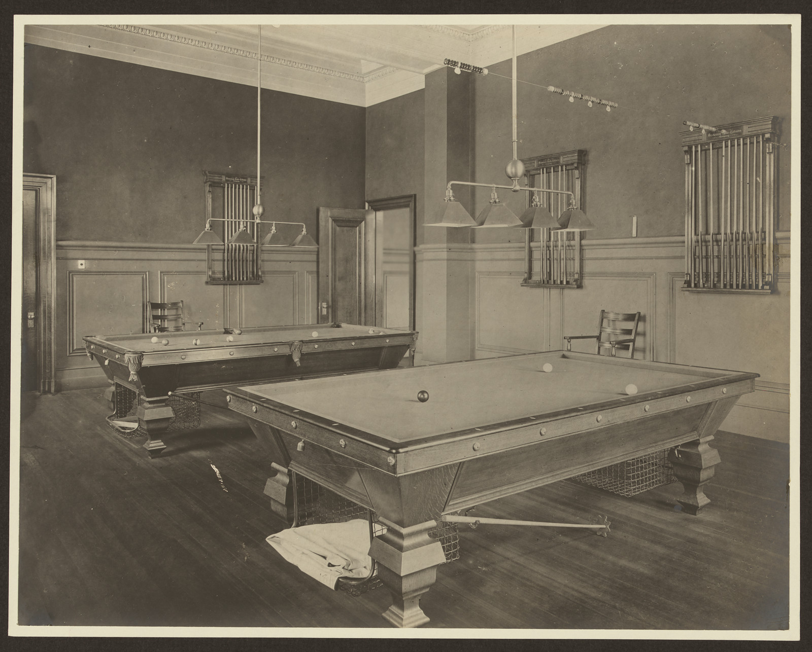 Billiard room with two pool tables and cue racks — historic image