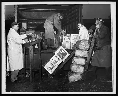 Market workers unloading Boy Blue apple crates and produce bags