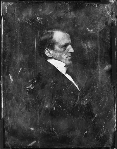 Profile portrait of a man in dark coat and white collar