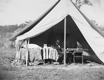 Two men seated inside a Civil War army tent