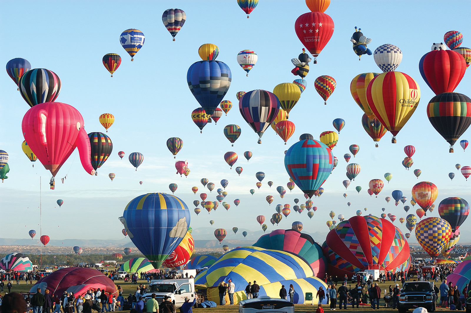 Hot air balloons mass ascension over a field with crowds — historic image