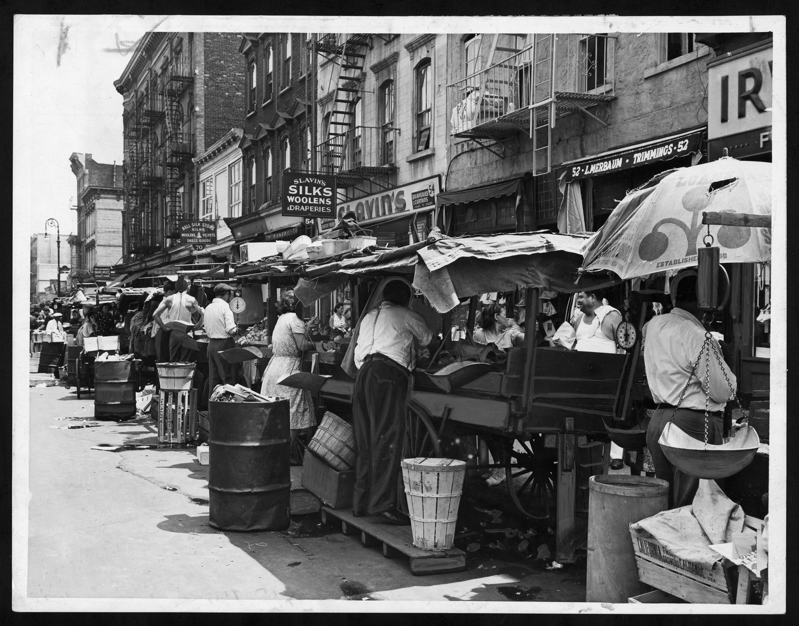 Pushcart market street with vendors and storefront signs — historic image