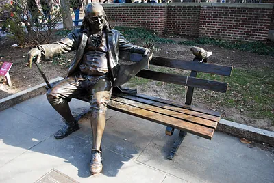 Bronze statue of Benjamin Franklin seated on a bench