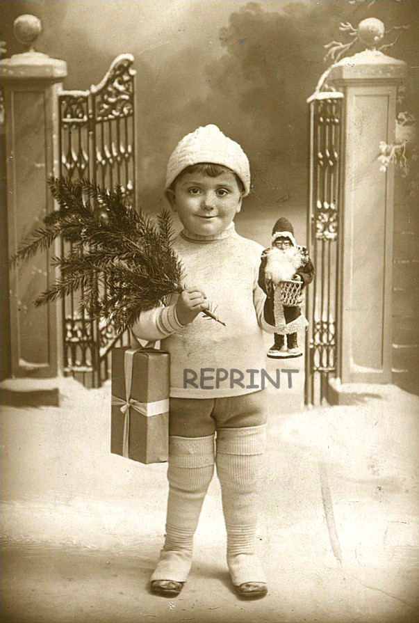 Child in winter hat holding Christmas tree and gift — historic image