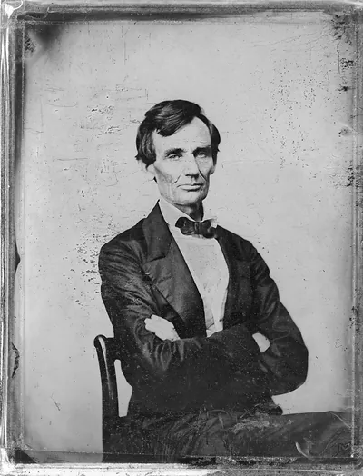 Seated man with crossed arms, bow tie, tintype portrait