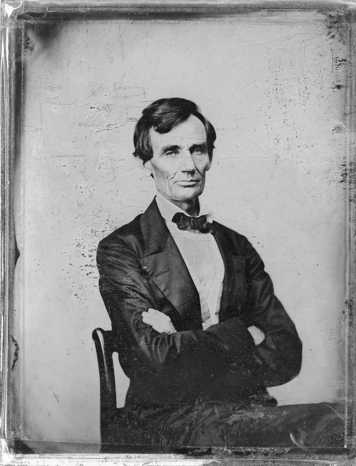 Seated man with crossed arms, bow tie, tintype portrait — historic image