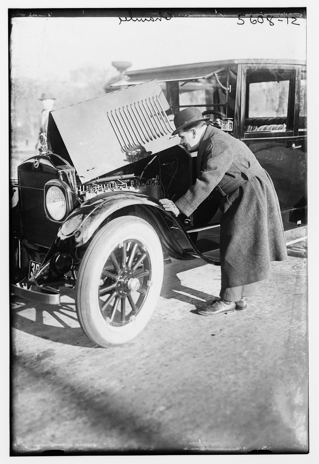 Chamlee looking at motor of auto, n/a — historic photograph