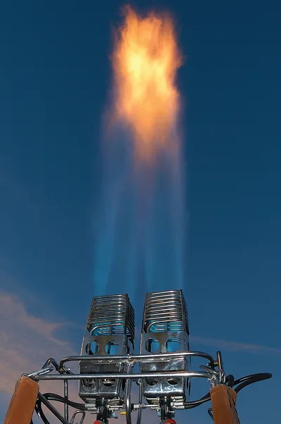 Hot air balloon burner flaming against blue sky