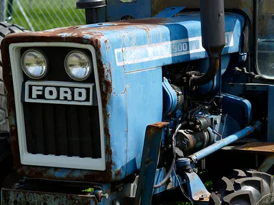Rusty blue Ford tractor front with headlights and grille