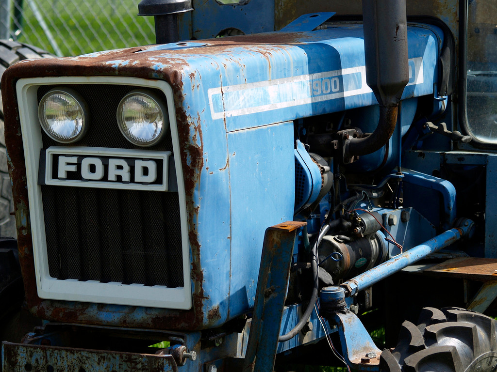 Rusty blue Ford tractor front with headlights and grille — historic image