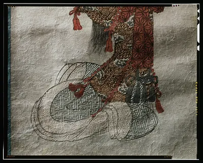 Patterned silk object with red tassels on paper