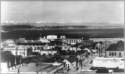[Bird's-eye view of Olympia, Washington with snow-capped Olympic Range in background]