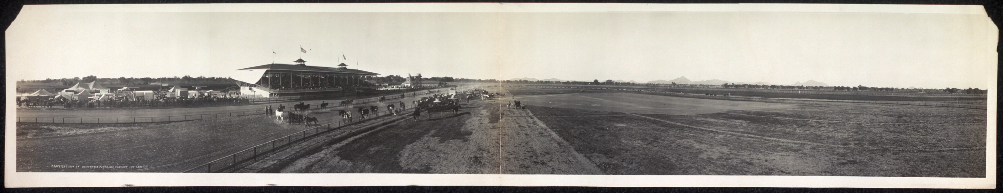 Panoramic view of grandstand and racetrack with horses — historic image
