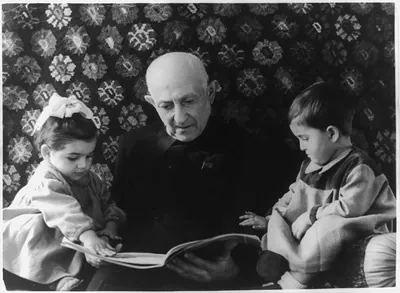[Yerevan, Armenian S.S.R.: Elderly man reading to 2 small children]