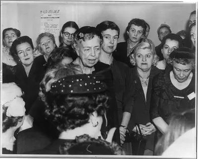 [Eleanor Roosevelt Roosevelt, 1884-1962, half length, standing with group of women, facing right, making address at the house warming of the new headquarters of the Democratic Women's Workshop in New York City]