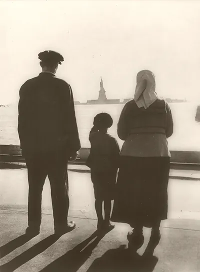 [Immigrant family looking at Statue of Liberty from Ellis Island]
