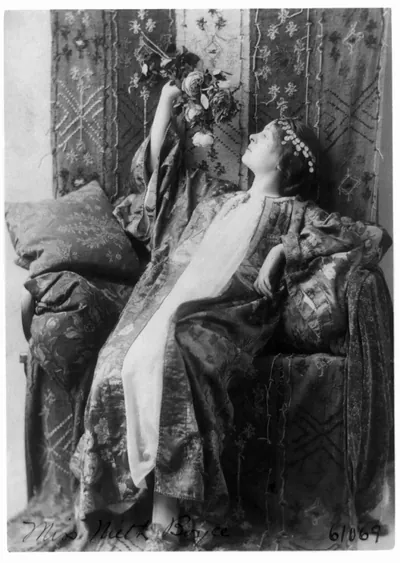 [Neith Boyce Hapgood,full-length portrait, seated, left profile, wearing ornamental costume and holding up roses]