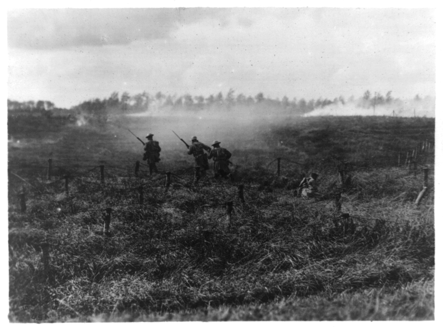 Inf. advancing on path through barbed wire entanglements, which tank has just made. One man has fallen over the barbed wire. 107th Inf., 27th Div., near Beauquesnes, Somme, France, 1918 Sept. 13. — historic photograph