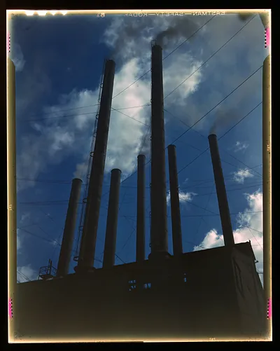 Tall industrial smokestacks against a blue sky, film transparency