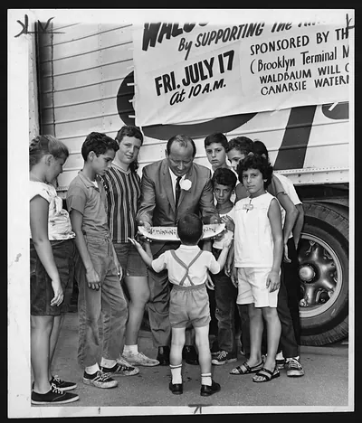 Man serving watermelon slices to children at Waldbaum event