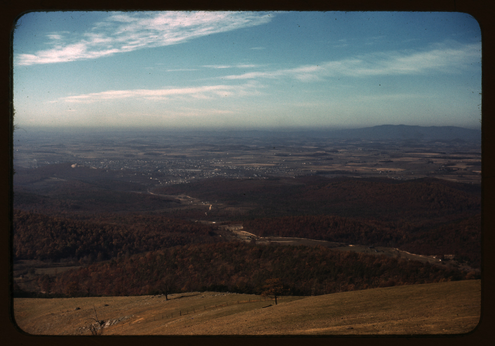 Wooded valley and distant town seen from a ridge overlook — historic image
