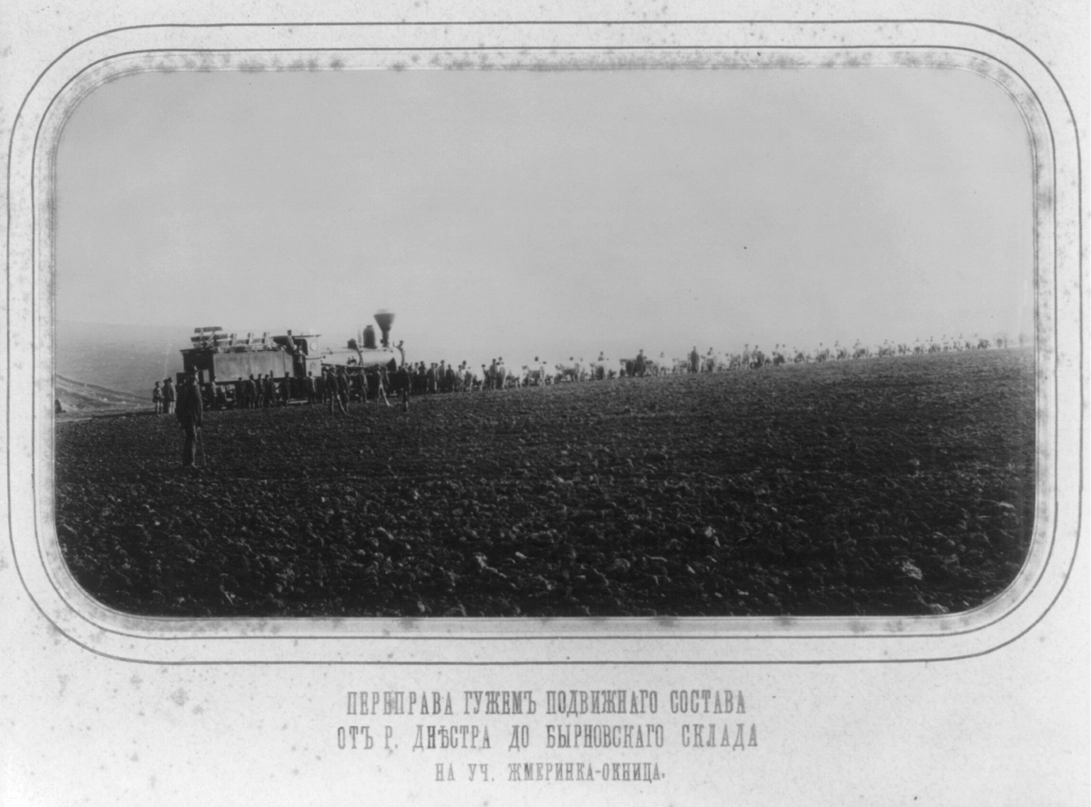 [Railroad construction in the Ukraine, 1890-1894: constr. locomotive following long line of men and oxen], [between 1890 and 1894] — historic photograph
