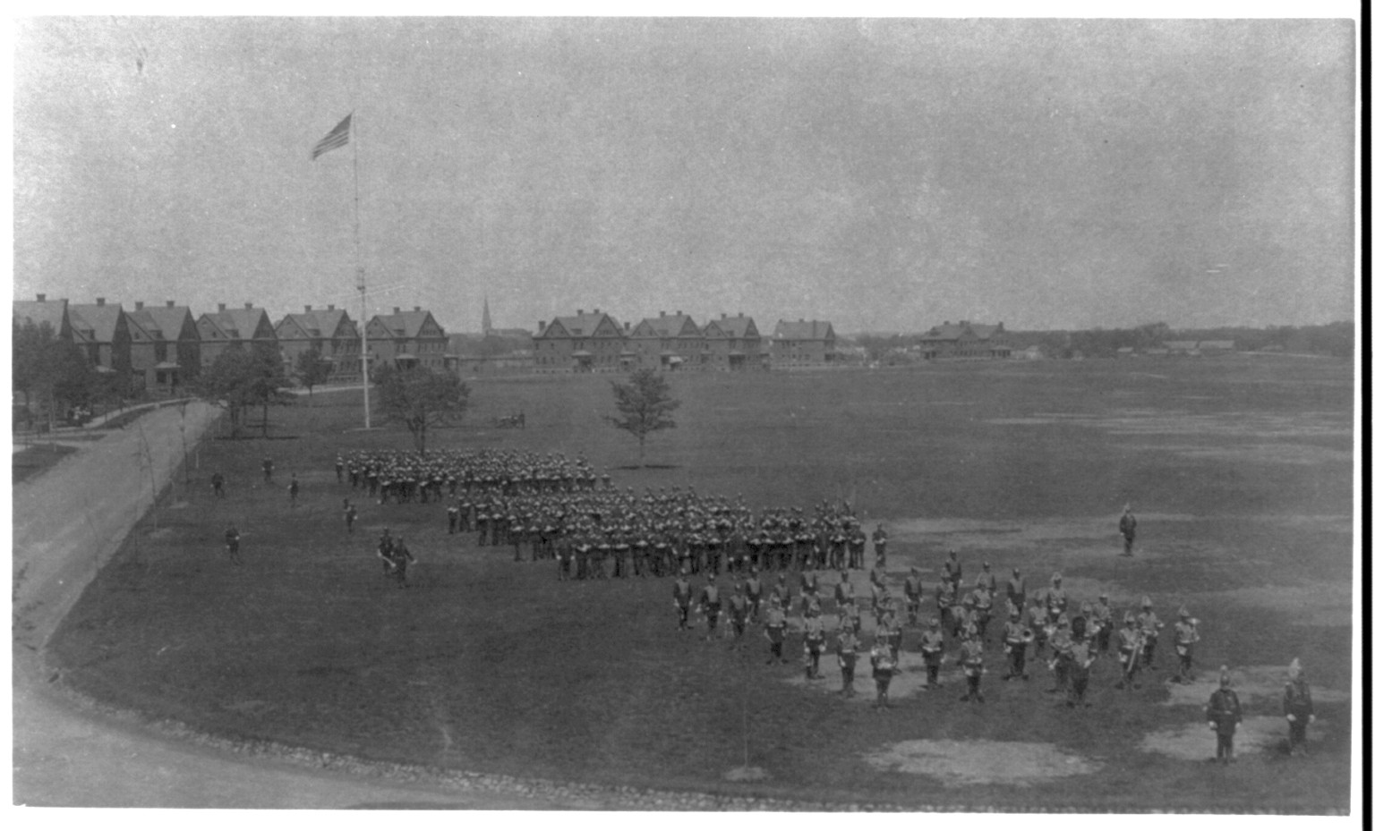 [U.S. Army units in full dress on parade grounds, led by band; panorama of drill field] — historic photograph