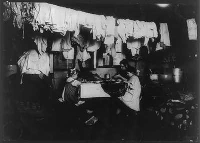 4 P.M. Ceru family, 143 Thompson St., near tenement, N.Y. In this dirty attic home with a dog and a cat adding to the other filth that accumulates, these three make artificial leaves. The little five-year-old helps some. She was sighing, Tired." Her sister (about 10 years old) works until 9 P.M. some nights although she is near-sighted. At home she keeps her glasses on the shelf 1912. The 5-year-o