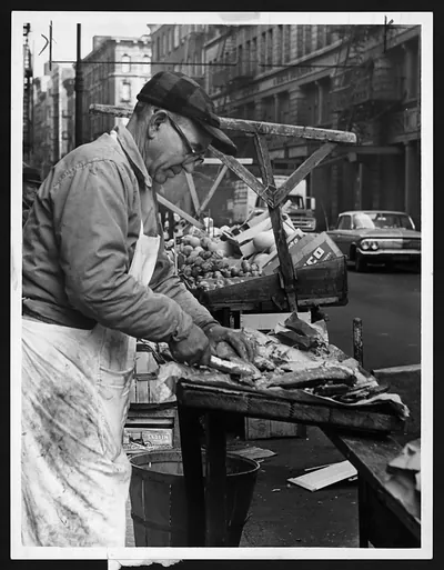 Man cleaning fish at a street market stall