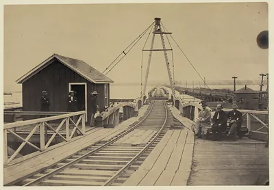 Railroad bridge trestle with derrick and seated men