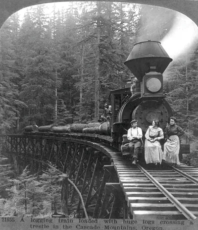 A logging train loaded with huge logs crossing a trestle in the Cascade Mountains, Ore.