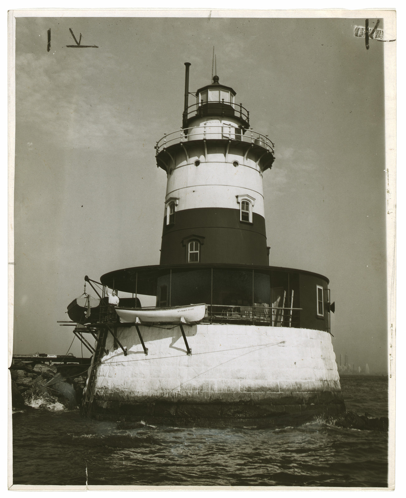Lighthouse on stone base with lantern tower and boat — historic image