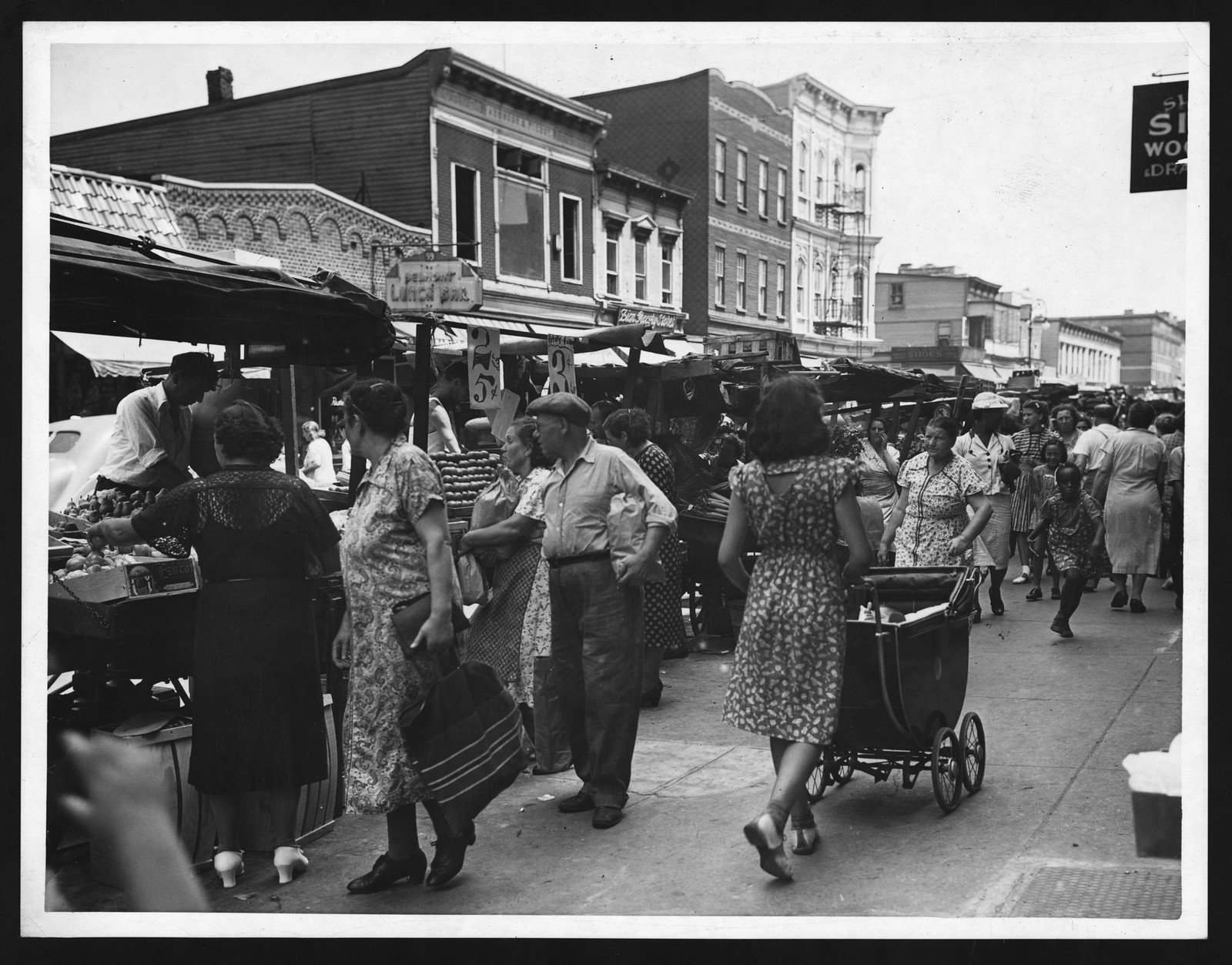 Crowded street market with shoppers and a baby carriage — historic image