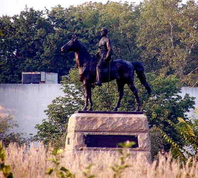Bronze equestrian statue on granite pedestal among trees