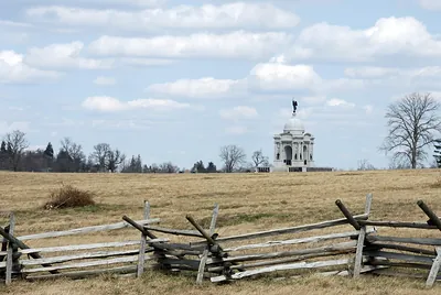 Domed monument across grassy field behind split-rail fence