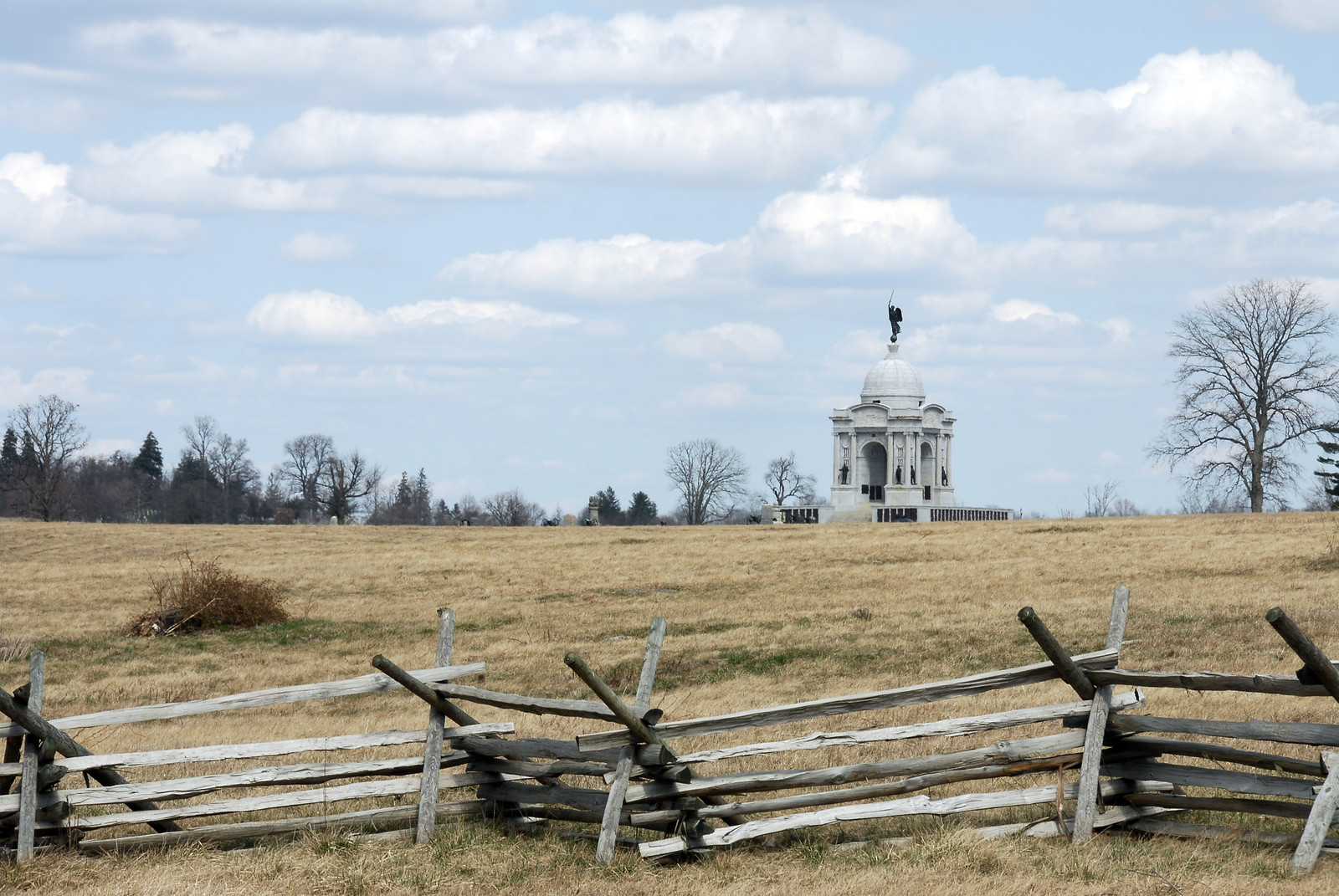 Domed monument across grassy field behind split-rail fence — historic image