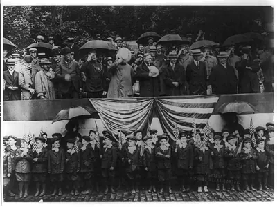 [Group of spectators including uniformed grammar school boys standing with two nuns in the rain, at a patriotic parade in Boston, Mass.]