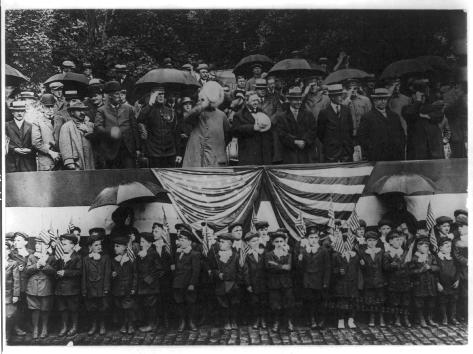[Group of spectators including uniformed grammar school boys standing with two nuns in the rain, at a patriotic parade in Boston, Mass.], 1916 July 4. — historic photograph
