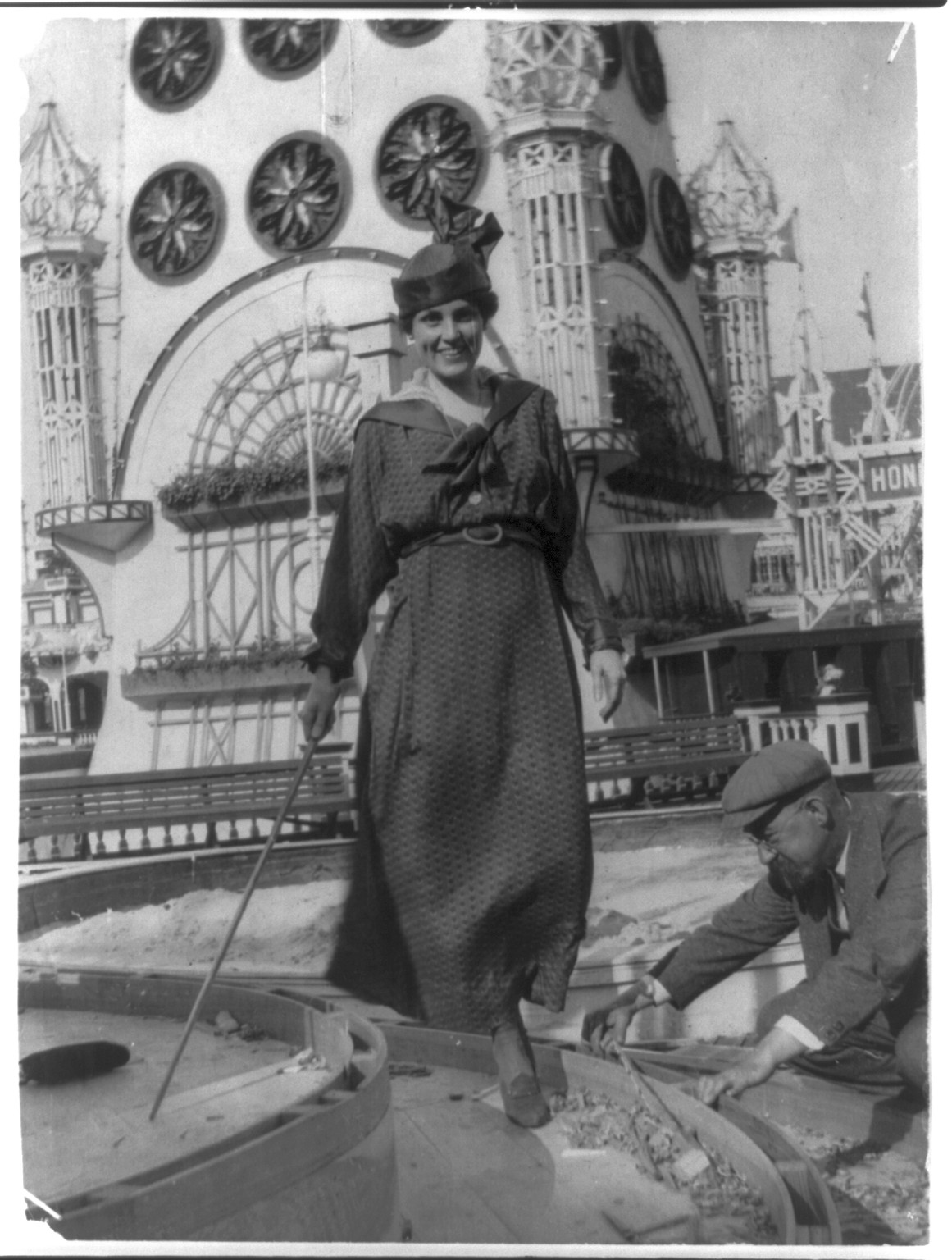 Woman in hat standing on wooden barrel at an exposition — historic image