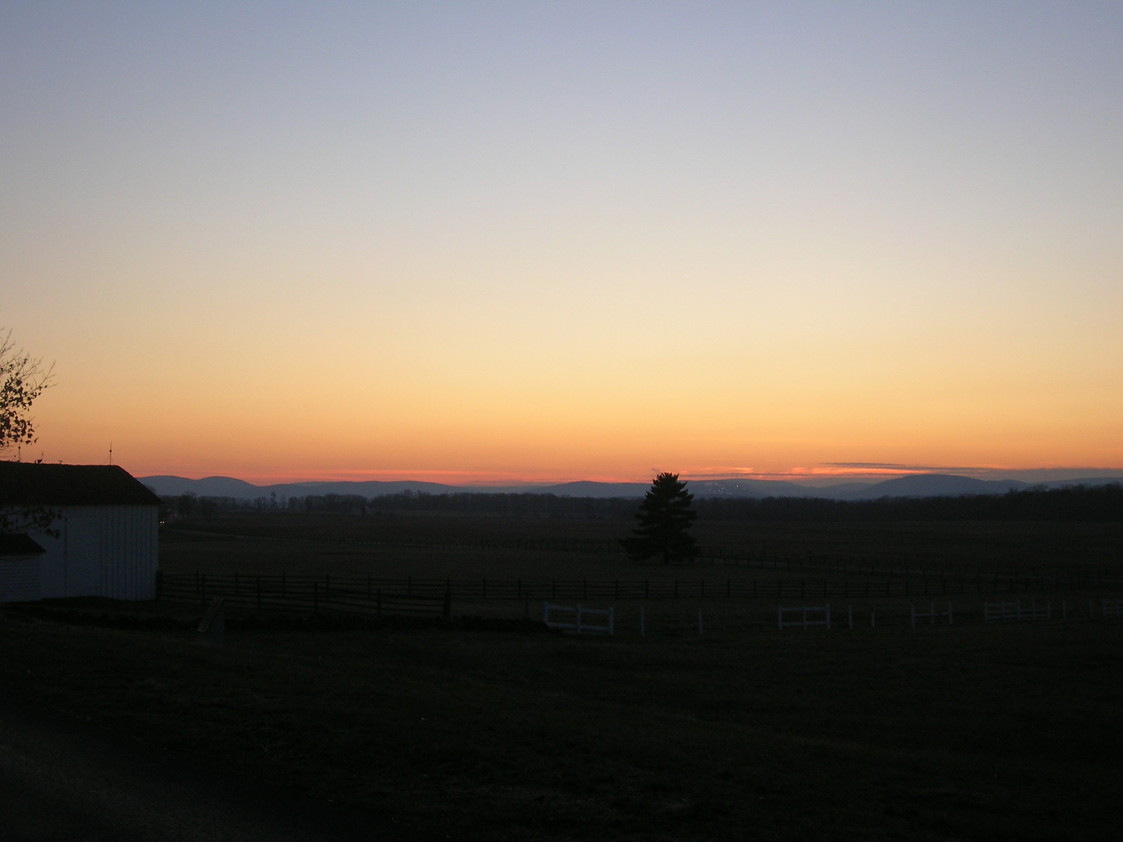 Sunset over rural fields with barn and distant hills — historic image