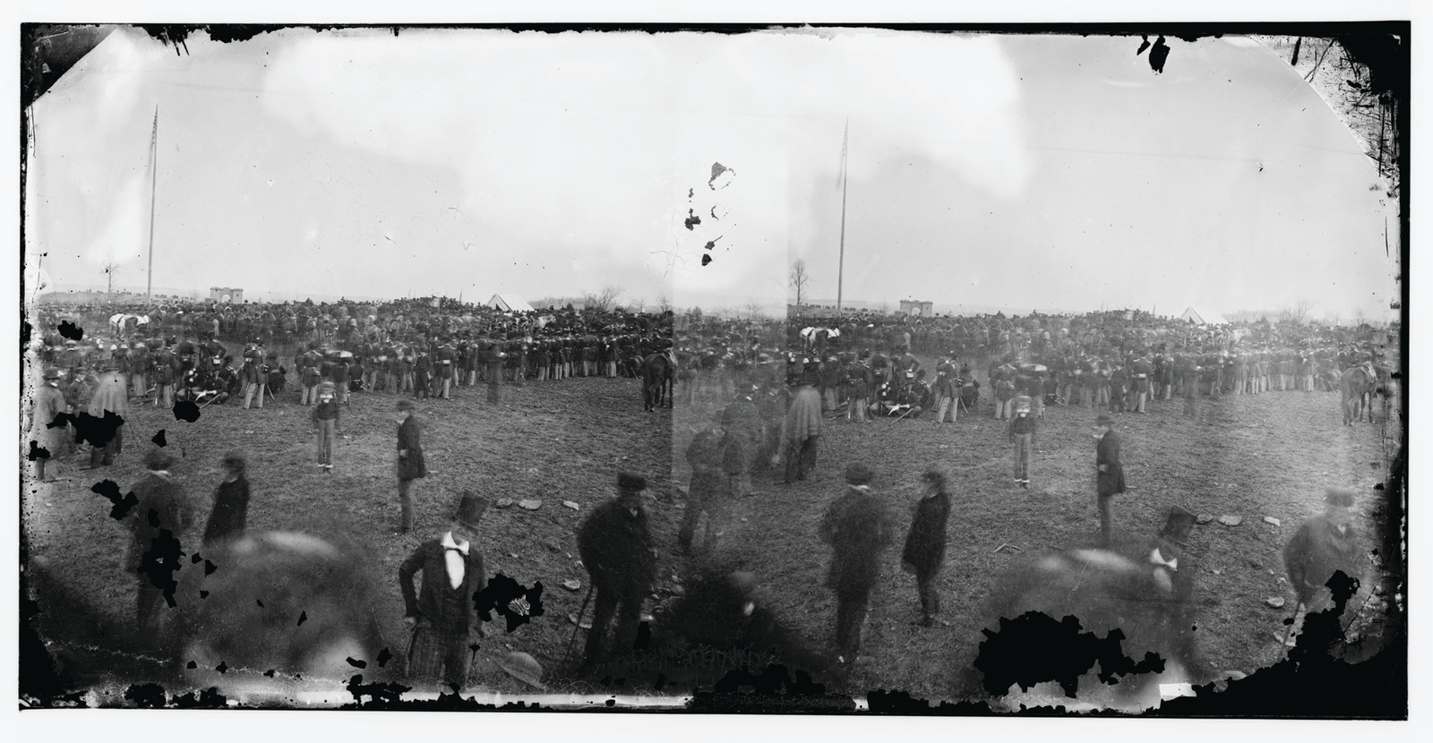 Large crowd of men on open field, Gettysburg, with flagpoles — historic image