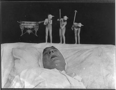 Motion picture still of a sleeping man with small figures