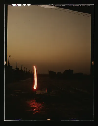 Railroad yard at dusk with a glowing light streak