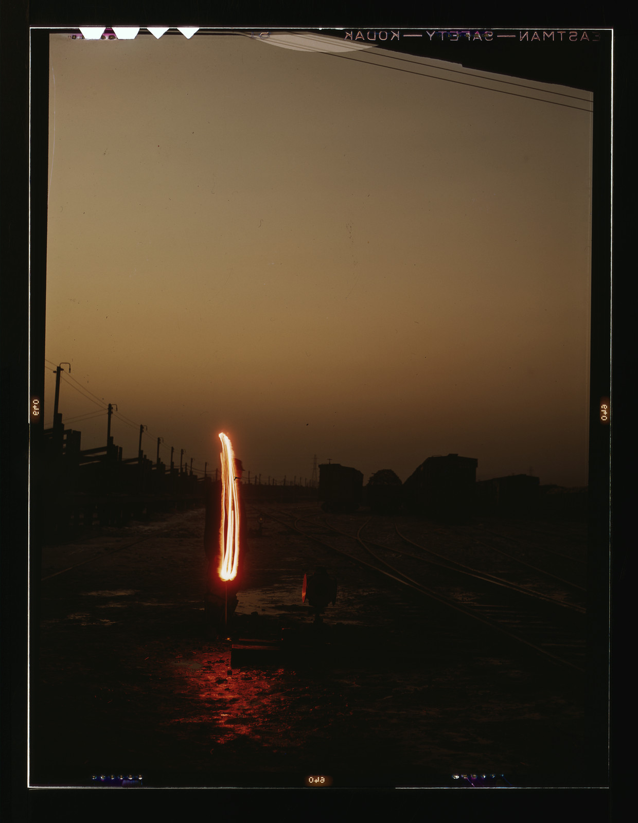 Railroad yard at dusk with a glowing light streak — historic image