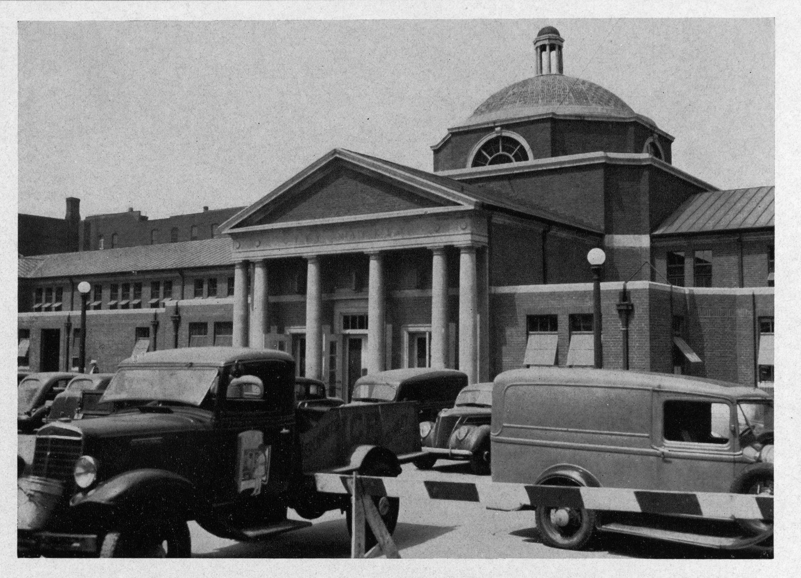 Domed market building with parked trucks and columns — historic image